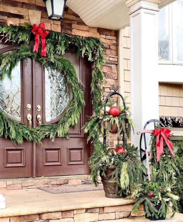 Front door decorated for Christmas with green leaves and ornaments