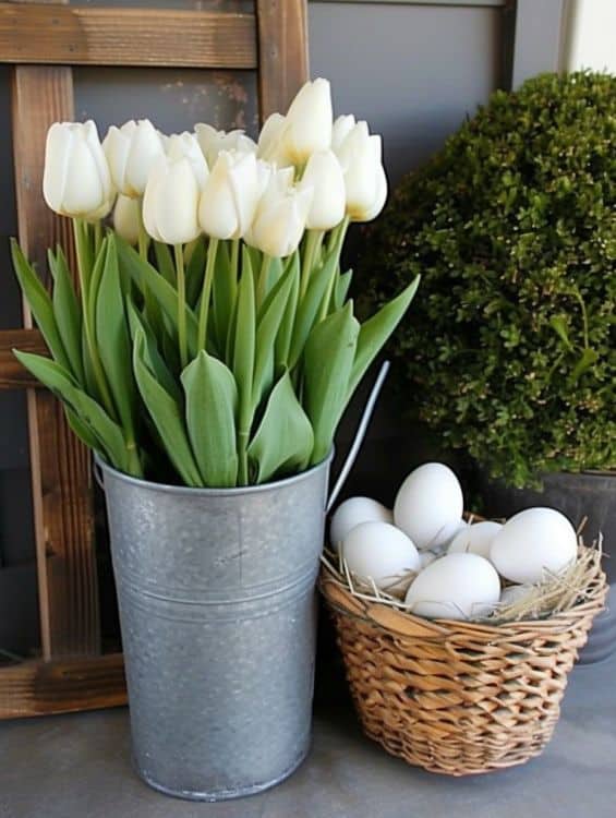 Front porch decorated with eggs in a vintage basket and beautiful tulips in a metal pot
