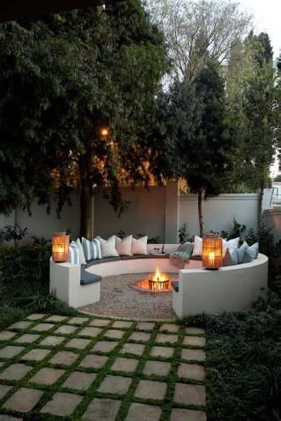 outdoor space with fire pit and throw pillow on the round concrete bench  #outdoorSpace #outdoorFurniture #backyardLighting #outdoorLights #OutdoorLighting #firepit #backyardFurniture #backyardLandscaping #backyardLandscapingIdeas #landscaping #cheapLandscapingIdeas #backyard #landscaping #curbAppeal