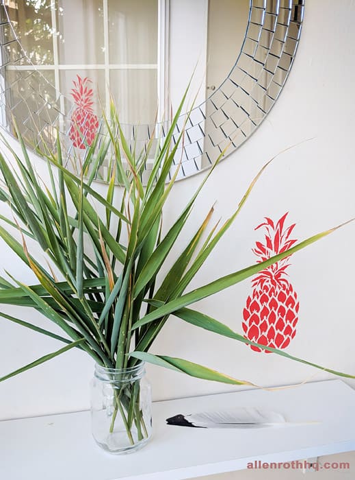 stenciled pineapple paint on the wall beside a plant vase #diy #stenciling #frontdoor #pineapple #homeDecor #anestwithayard #stencil #wallstencil