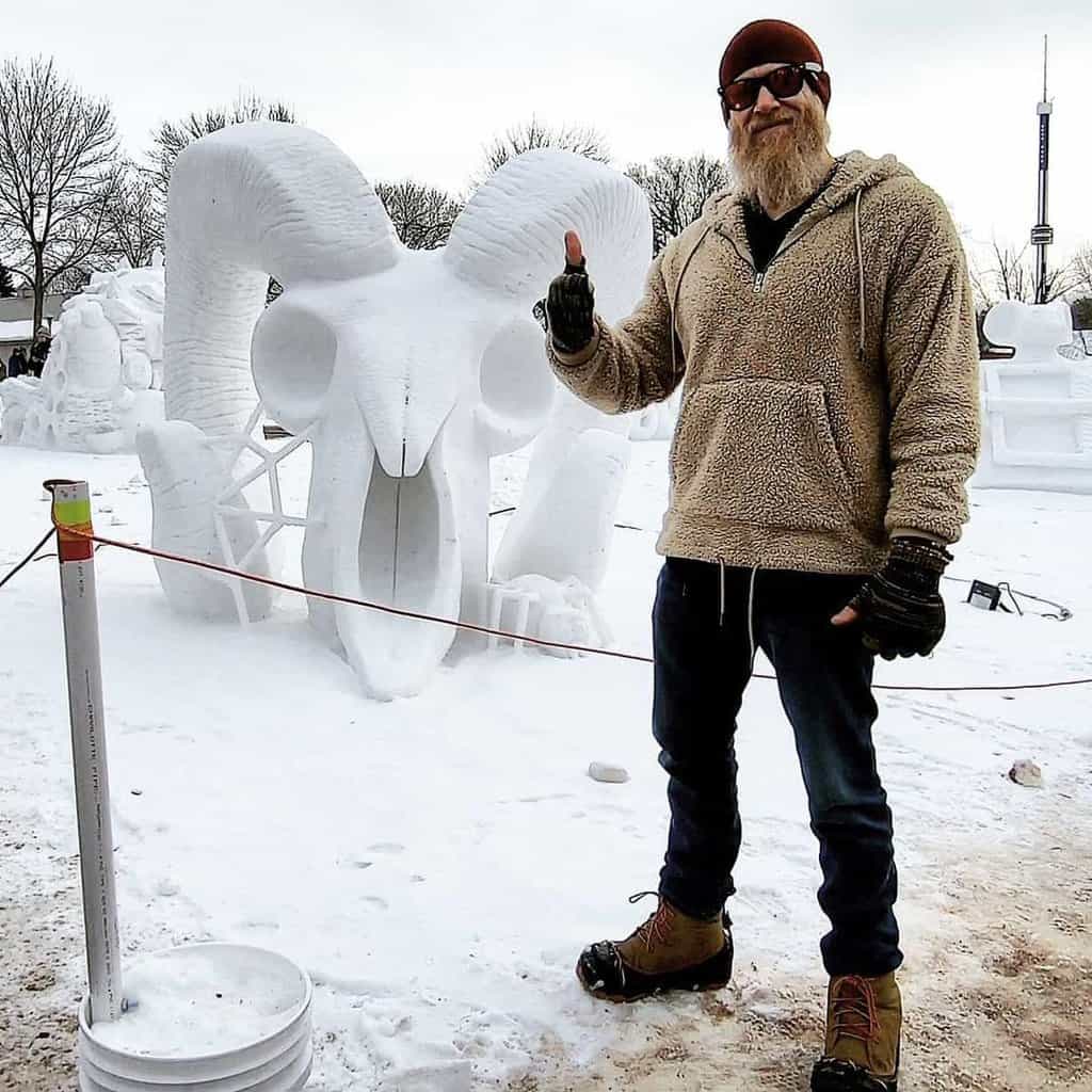 Man posing with a skull shape snow sculpture