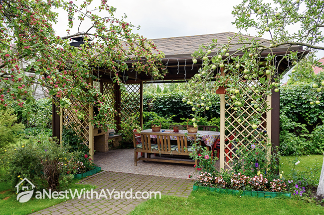 Summer vibes open wooden gazebo in a garden with apple trees and flowers