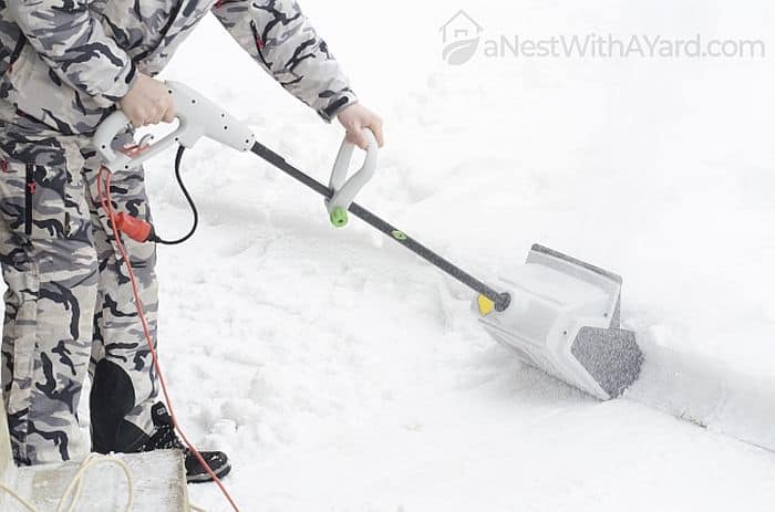 A man operating an electric snow shovel