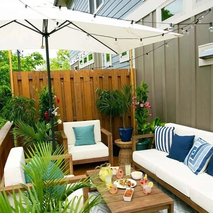 A patio styled with a comfortable sofa and an umbrella