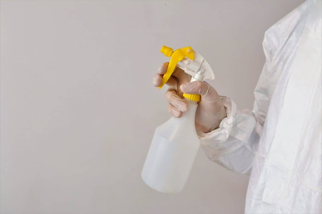 A spray bottle held by a gloved hand