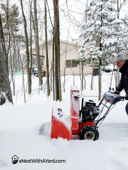 Man cleaning snow with a red snow blower