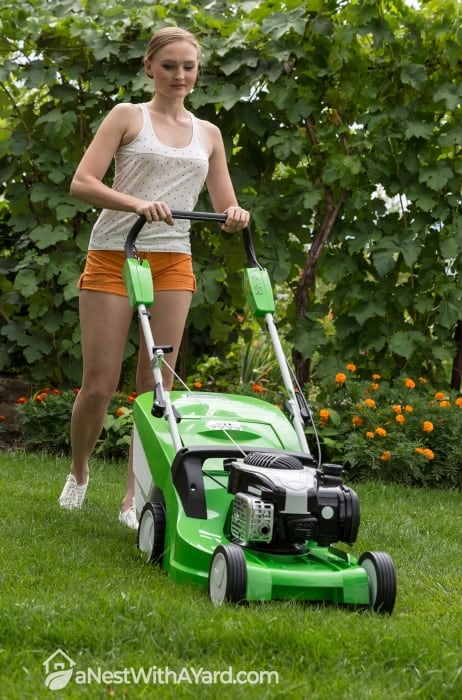 A woman mowing a lawn with a lawn mower
